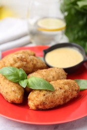 Photo of Tasty fried croquettes, basil and sauce on white marble table, closeup