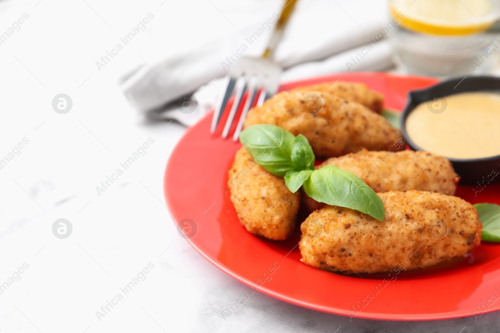 Tasty fried croquettes, basil and sauce on white marble table, closeup. Space for text Photo of Tasty fried croquettes, basil and sauce on white marble table, closeup. Space for text