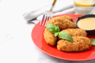 Photo of Tasty fried croquettes, basil and sauce on white marble table, closeup. Space for text