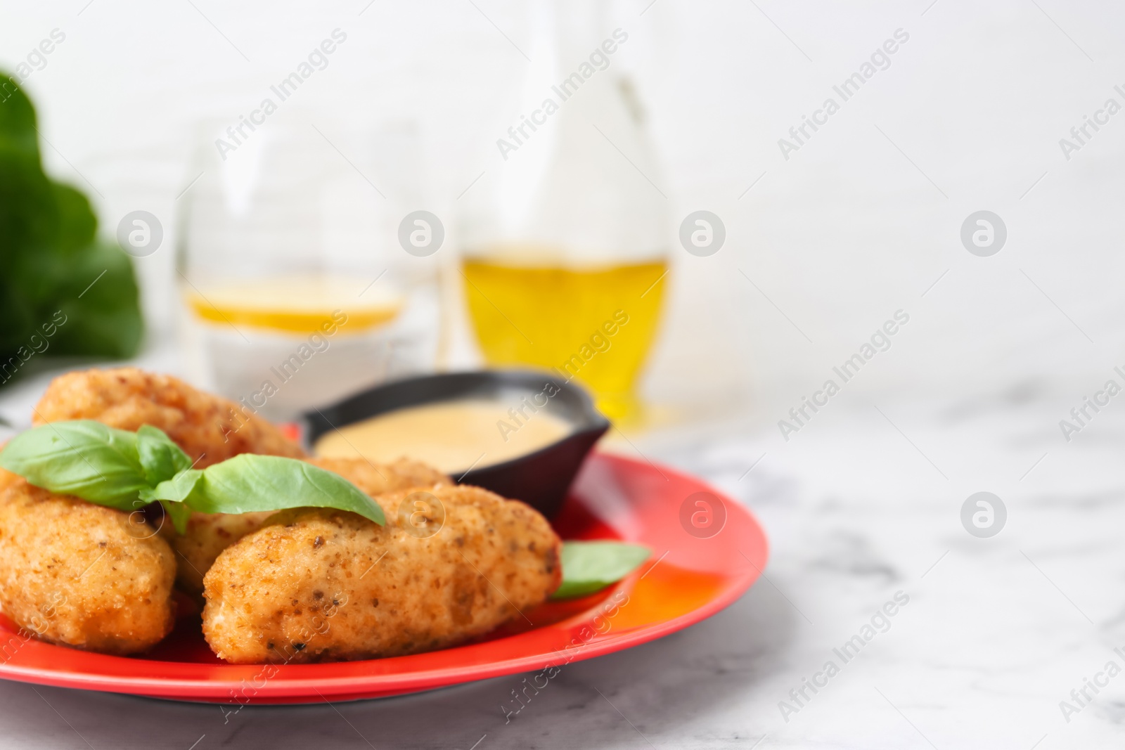 Tasty fried croquettes, basil and sauce served on white marble table, closeup. Space for text Photo of Tasty fried croquettes, basil and sauce served on white marble table, closeup. Space for text