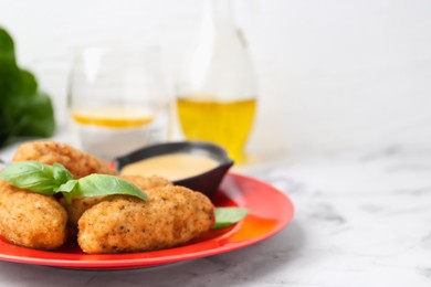 Photo of Tasty fried croquettes, basil and sauce served on white marble table, closeup. Space for text