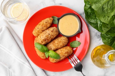 Photo of Tasty fried croquettes, basil and sauce served on white marble table, flat lay