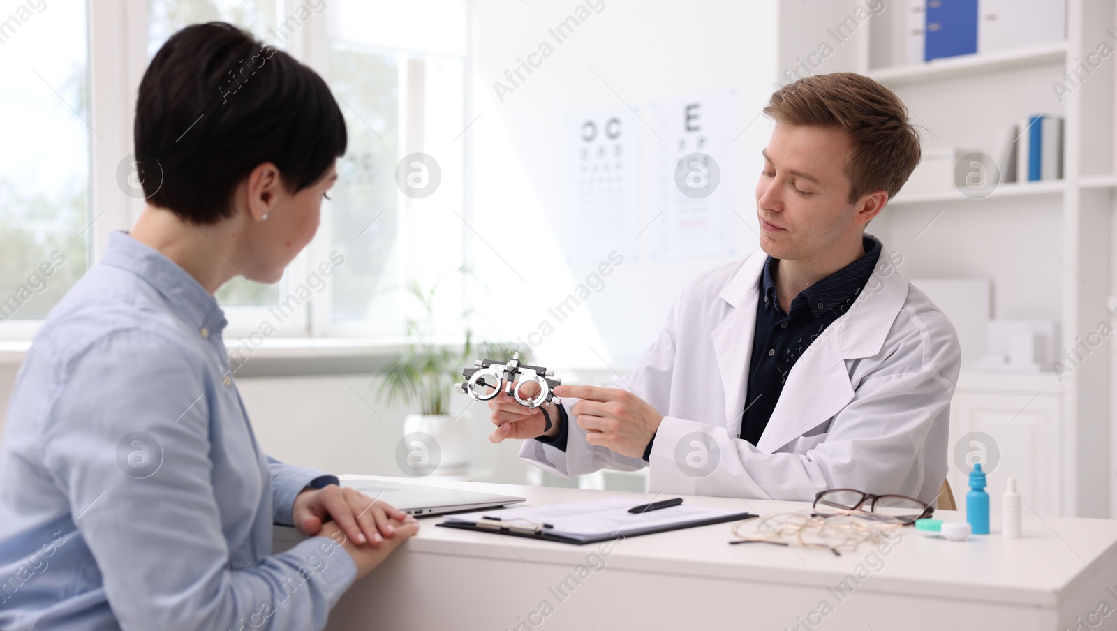 Ophthalmologist consulting woman at table in clinic Photo of Ophthalmologist consulting woman at table in clinic
