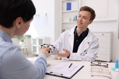 Photo of Ophthalmologist consulting woman at table in clinic