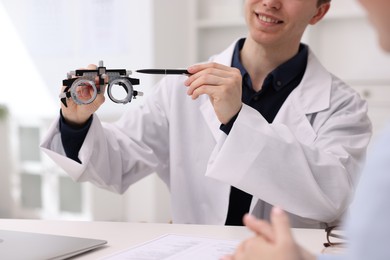 Photo of Ophthalmologist consulting woman at white table in clinic, closeup