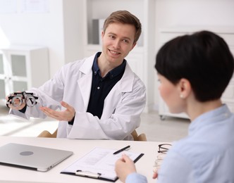 Photo of Ophthalmologist consulting woman at white table in clinic