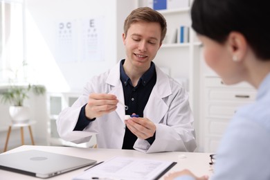 Photo of Ophthalmologist consulting woman at white table in clinic