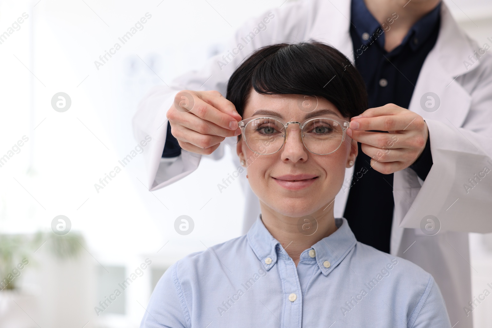 Ophthalmologist giving glasses to patient in clinic, closeup Photo of Ophthalmologist giving glasses to patient in clinic, closeup