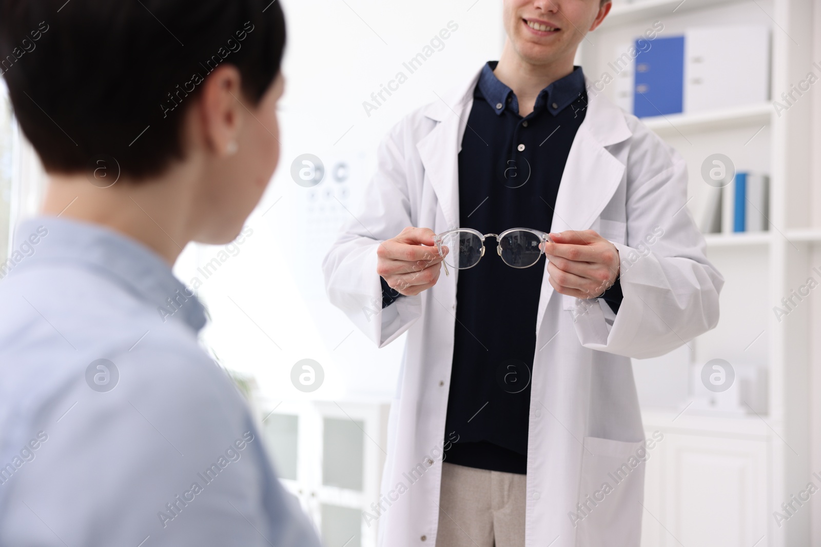 Ophthalmologist giving glasses to patient in clinic, closeup Photo of Ophthalmologist giving glasses to patient in clinic, closeup