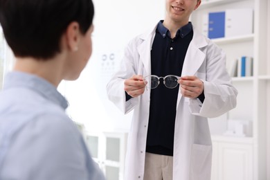 Photo of Ophthalmologist giving glasses to patient in clinic, closeup