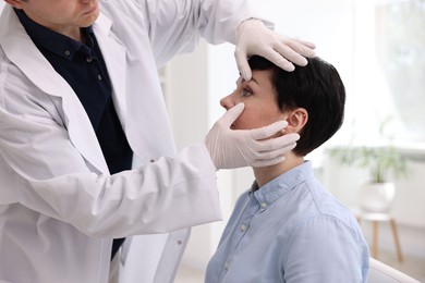 Photo of Professional ophthalmologist examining patient's vision in clinic, closeup