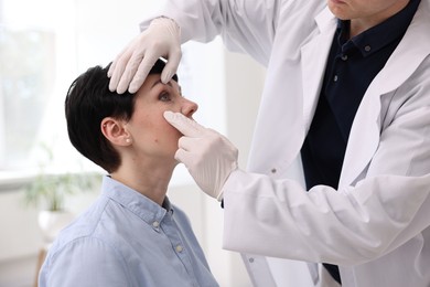 Photo of Professional ophthalmologist examining patient's vision in clinic, closeup