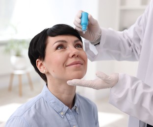 Photo of Ophthalmologist applying medical drops onto patient's eye in clinic, closeup