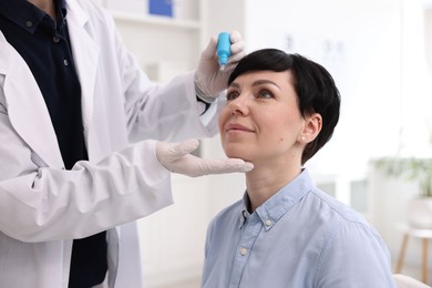 Photo of Ophthalmologist applying medical drops onto patient's eye in clinic, closeup