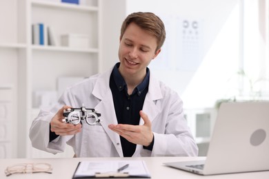 Photo of Portrait of professional ophthalmologist with trial frame at white table in clinic