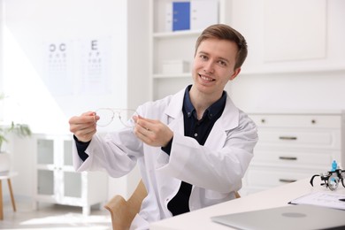 Photo of Portrait of professional ophthalmologist with glasses at white table in clinic