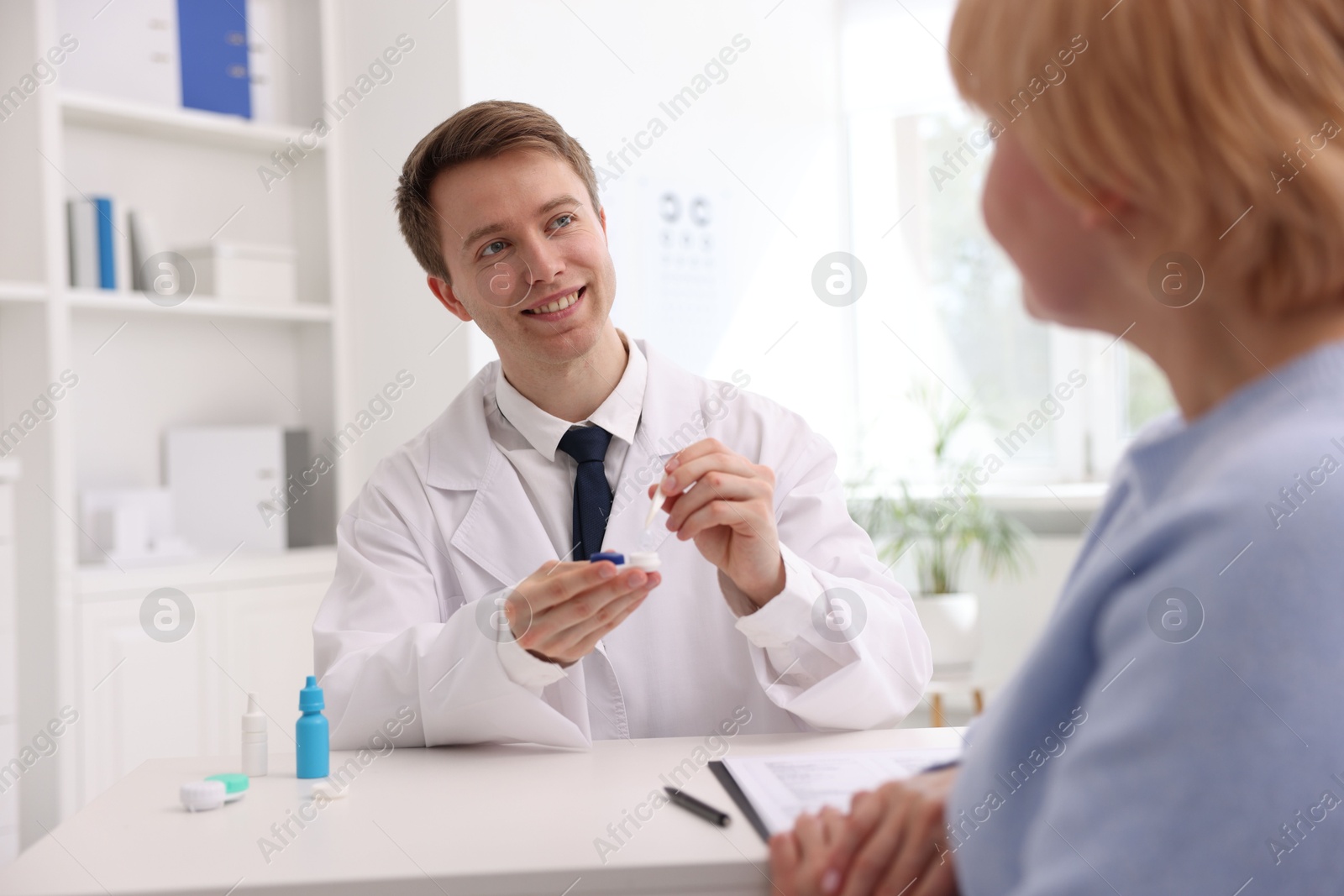 Ophthalmologist consulting senior woman at white table in clinic Photo of Ophthalmologist consulting senior woman at white table in clinic