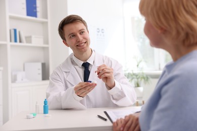 Photo of Ophthalmologist consulting senior woman at white table in clinic