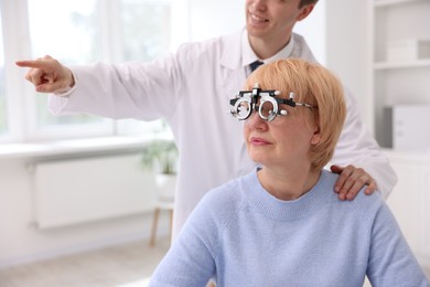 Photo of Ophthalmologist examining patient's vision with trial frame in clinic