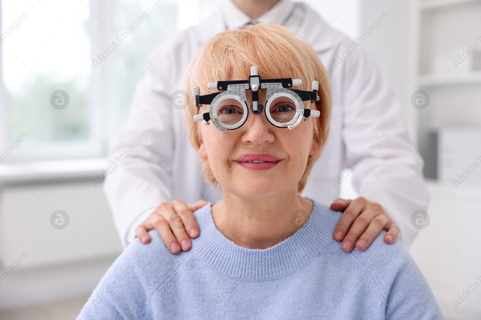 Ophthalmologist examining patient's vision with trial frame in clinic Photo of Ophthalmologist examining patient's vision with trial frame in clinic