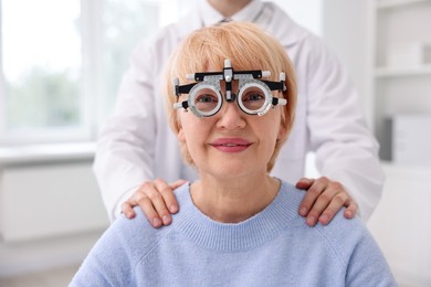 Photo of Ophthalmologist examining patient's vision with trial frame in clinic