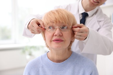 Photo of Ophthalmologist giving glasses to patient in clinic, closeup