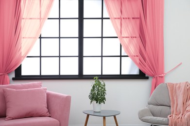 Image of Armchair and sofa near window with pink curtains in room. Interior design