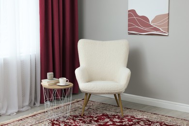 Image of Living room with armchair and burgundy color curtains. Interior design
