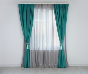 Image of Window with teal curtains in room. Interior design