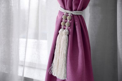 Image of Pink window curtains with tassel tieback, closeup view