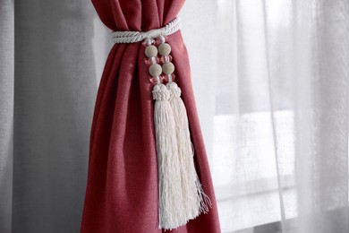 Image of Red window curtains with tassel tieback, closeup view