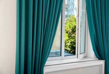 Image of Window with teal curtains in room. Interior design