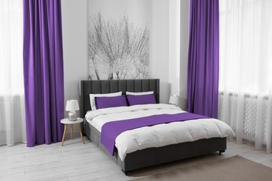 Image of Bed between windows with purple curtains in room. Interior design