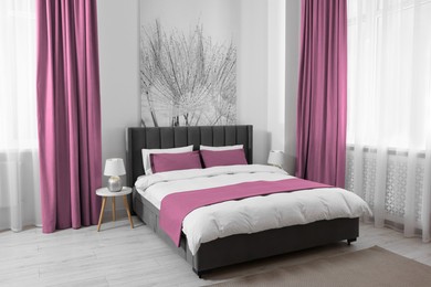 Image of Bed between windows with pink curtains in room. Interior design
