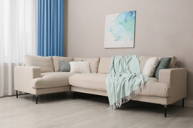 Image of Comfortable sofa near window with light blue curtains in room. Interior design