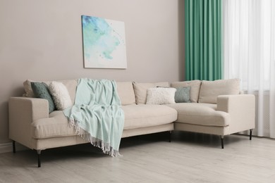 Image of Comfortable sofa near window with mint color curtains in room. Interior design