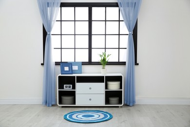Image of Window with pale blue curtains in room. Interior design