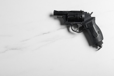Photo of Police equipment. One black gun on white marble table, top view. Space for text