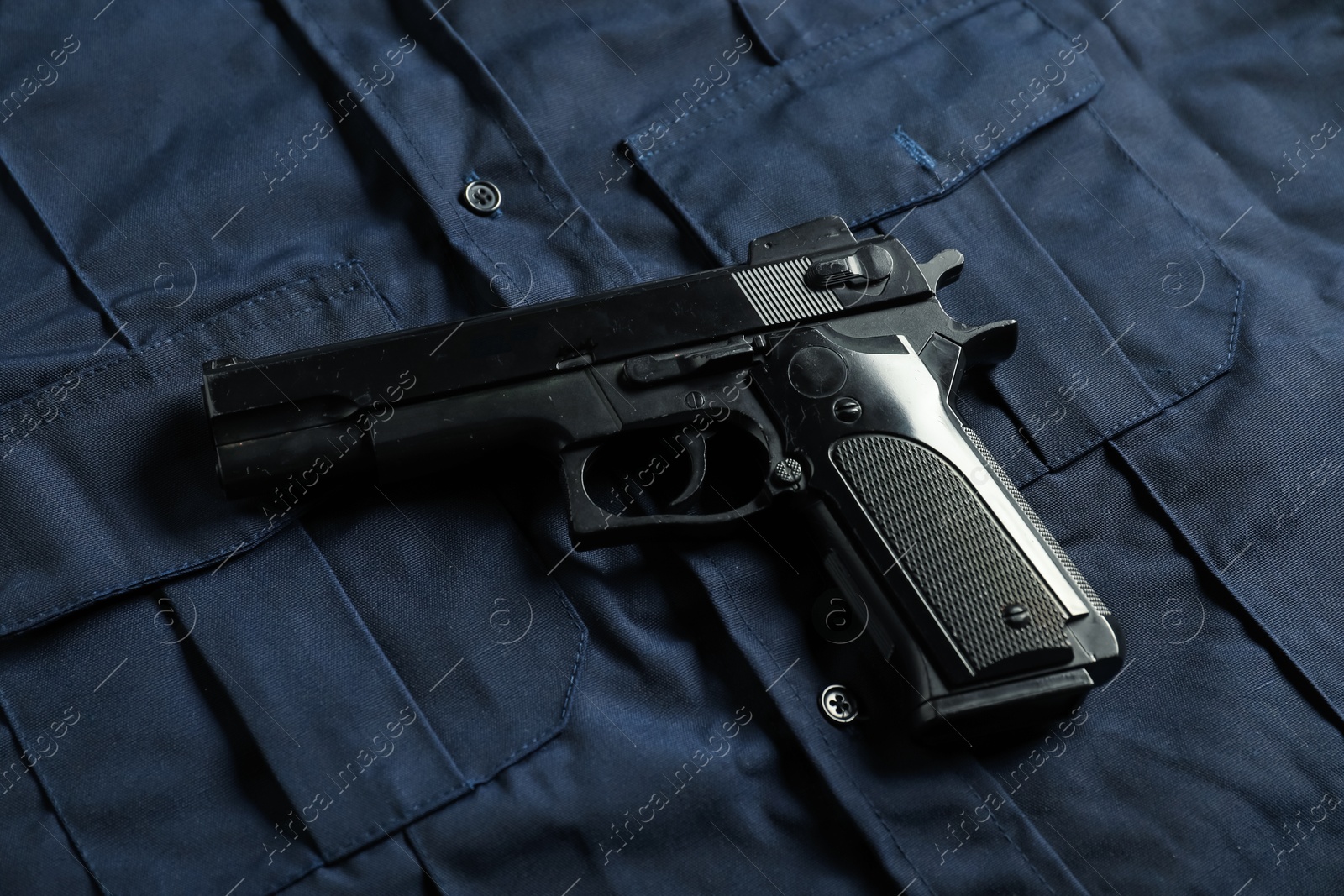 Black gun on dark blue uniform, above view. Police equipment Photo of Black gun on dark blue uniform, above view. Police equipment