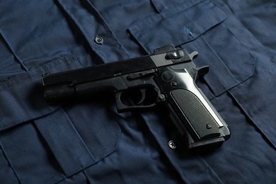 Photo of Black gun on dark blue uniform, above view. Police equipment
