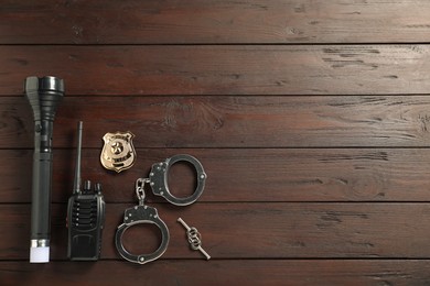 Photo of Different police equipment on wooden table, flat lay. Space for text