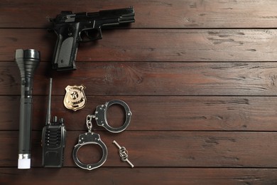 Photo of Different police equipment on wooden table, flat lay. Space for text