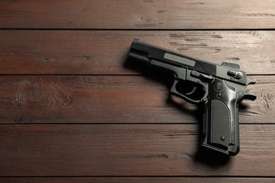 Photo of Police equipment. One black gun on wooden table, top view. Space for text
