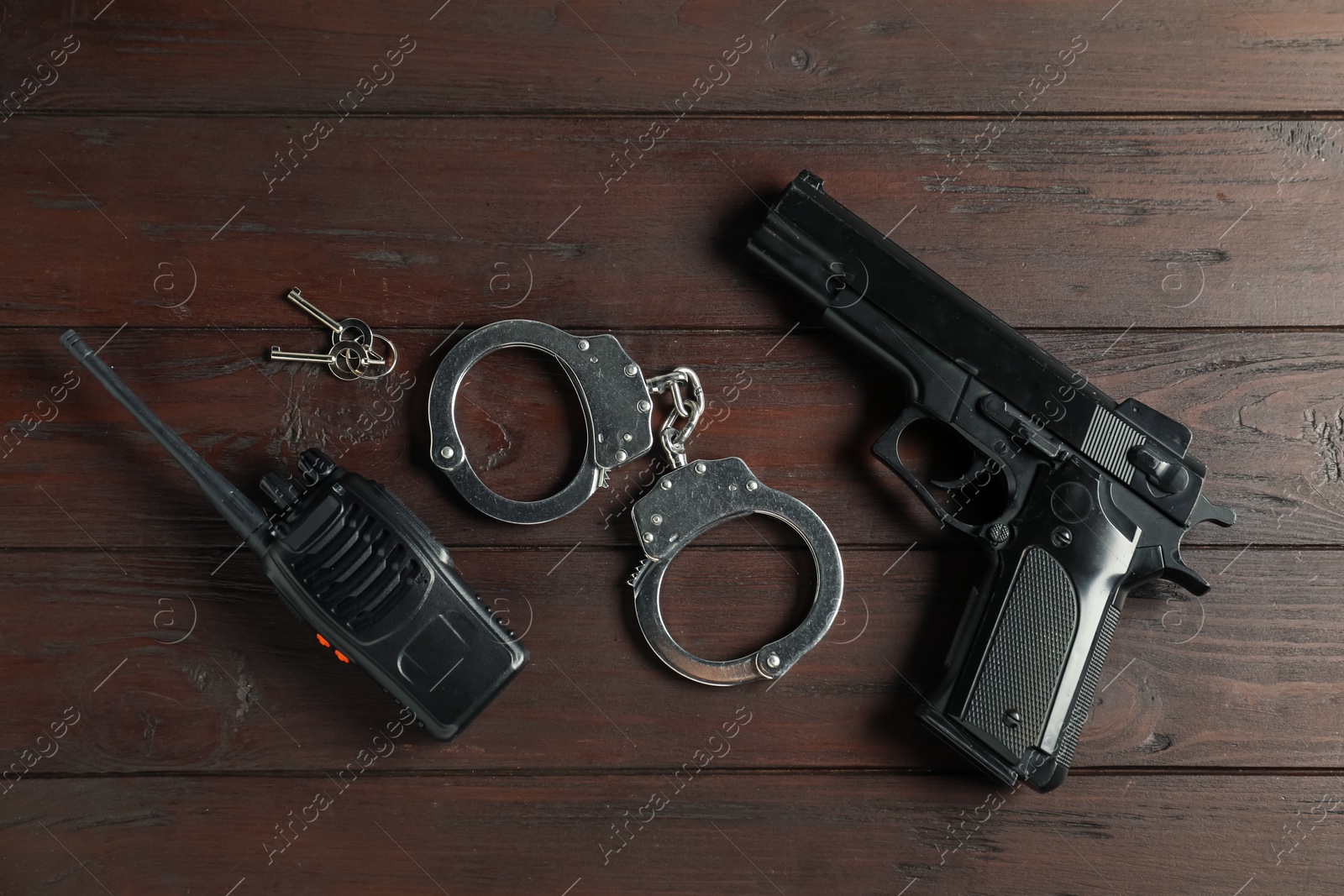 Walkie talkie, handcuffs, gun and keys on wooden table, flat lay. Police equipment Photo of Walkie talkie, handcuffs, gun and keys on wooden table, flat lay. Police equipment