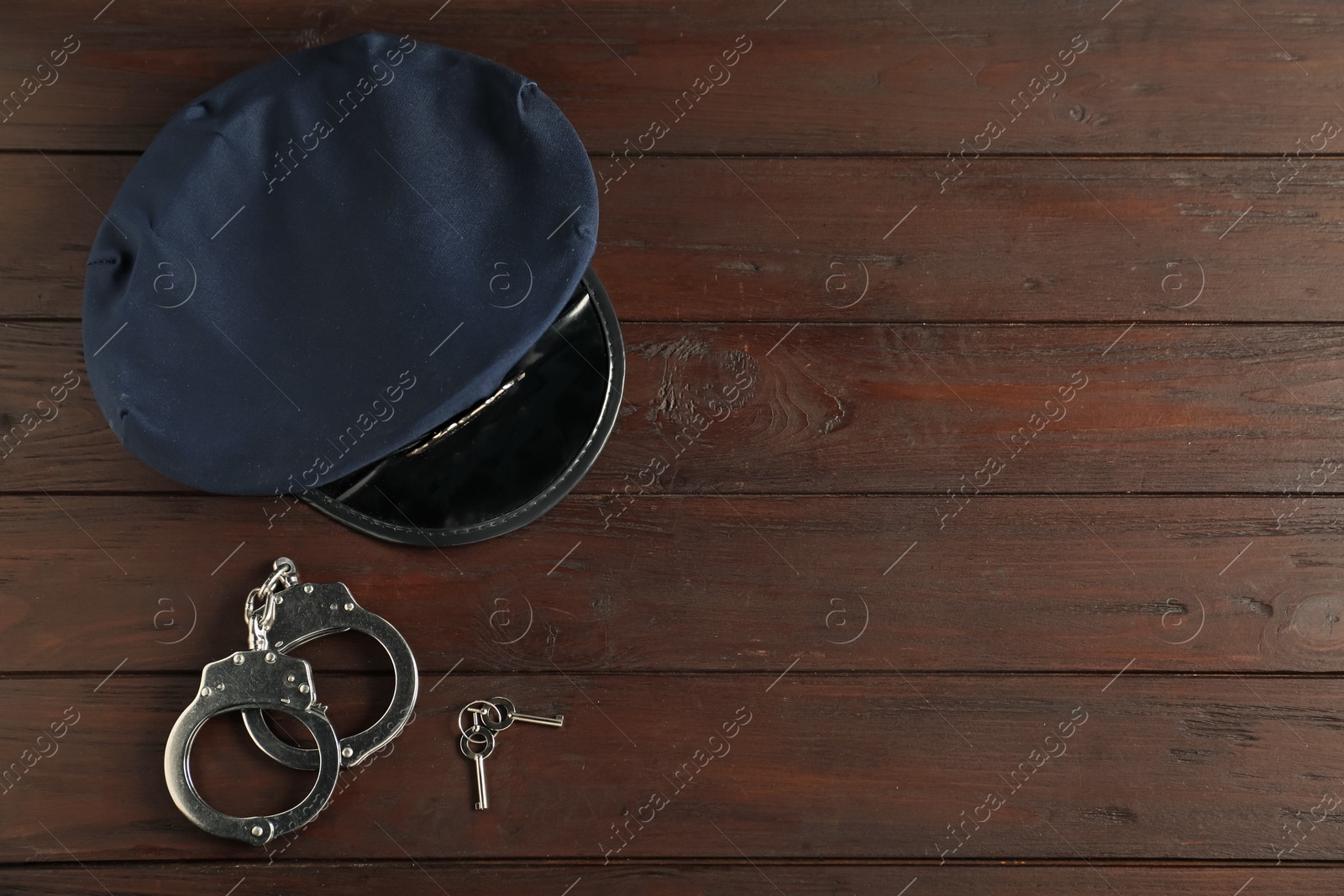 Police cap, handcuffs and keys on wooden table, flat lay Photo of Police cap, handcuffs and keys on wooden table, flat lay