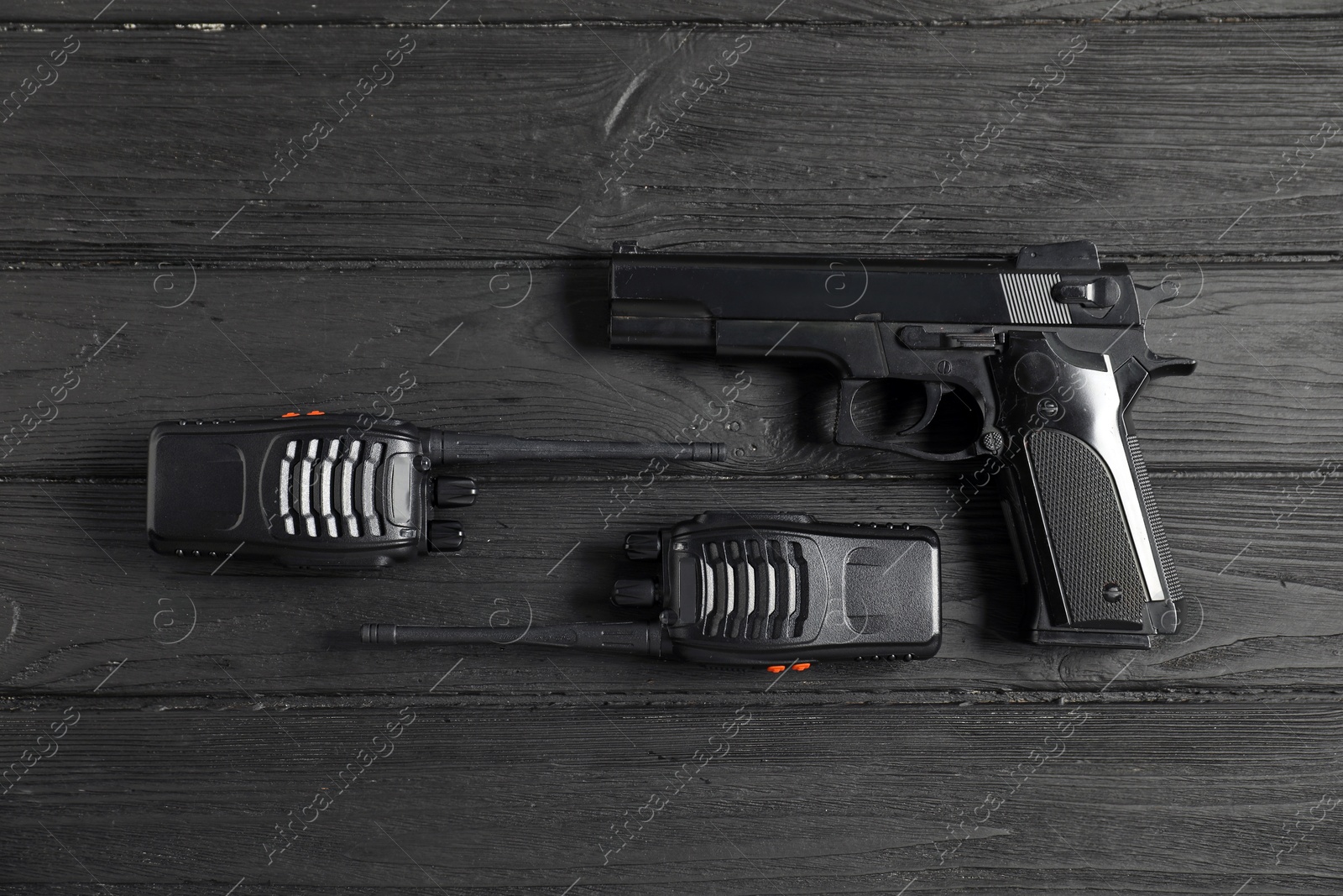 Gun and walkie talkies on black wooden table, flat lay. Police equipment Photo of Gun and walkie talkies on black wooden table, flat lay. Police equipment