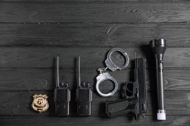 Photo of Different police equipment on black wooden table, flat lay