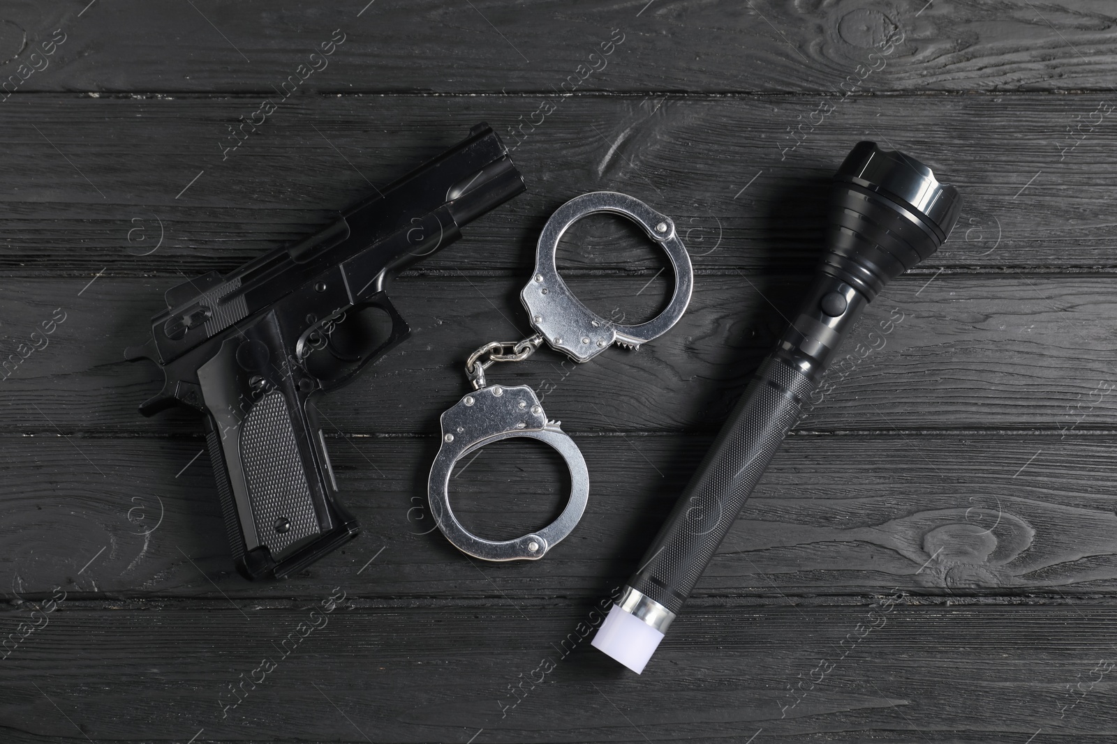 Gun, handcuffs and flashlight on black wooden table, flat lay. Police equipment Photo of Gun, handcuffs and flashlight on black wooden table, flat lay. Police equipment