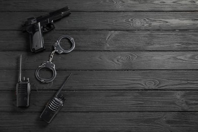 Photo of Different police equipment on black wooden table, flat lay. Space for text