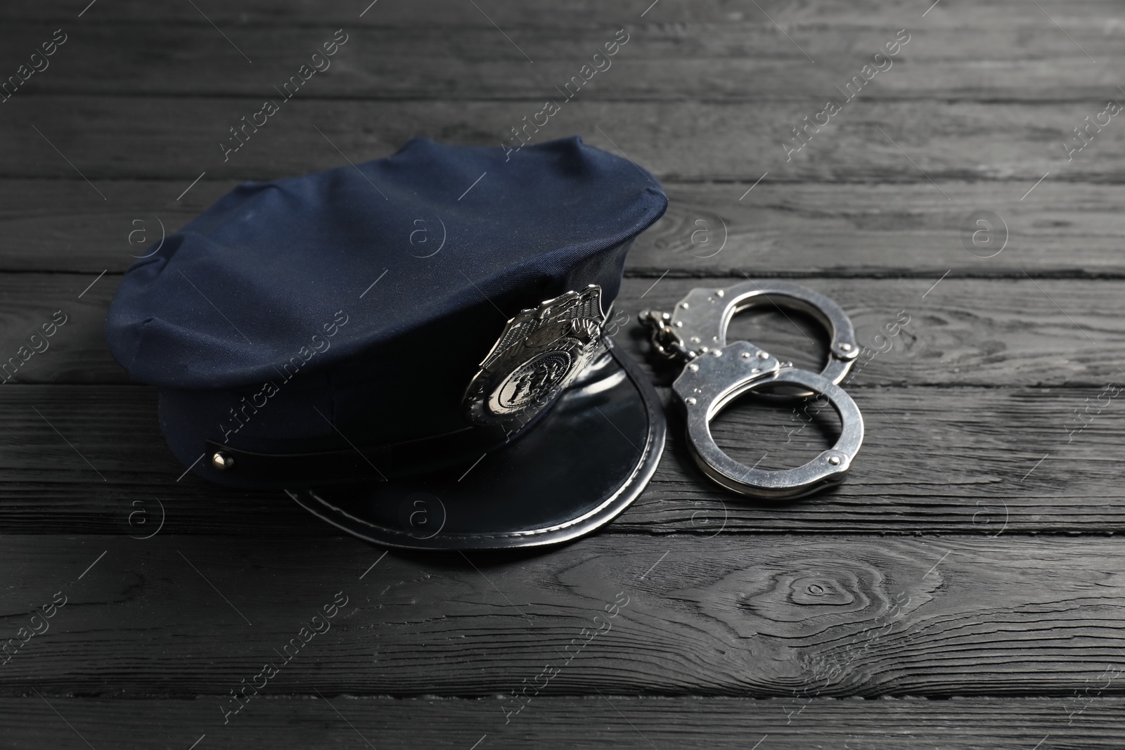Police cap and handcuffs on black wooden table, closeup Photo of Police cap and handcuffs on black wooden table, closeup